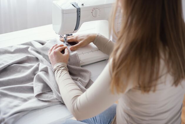 缝纫工高角度的女裁缝用缝纫机和布料服装针线活女