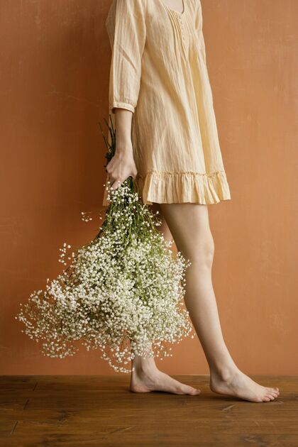 春天侧视图中的妇女摆姿势 同时举行花束的春天垂直花花