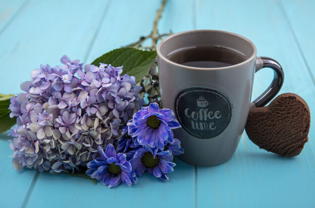 杯子一杯茶的侧视图 蓝色木质背景上有可爱的花朵风景木头蓝色
