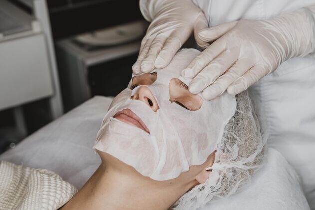 面部在水疗中心接受皮肤面膜治疗的年轻女人水疗女人化妆品