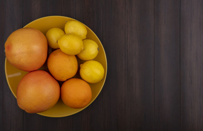 视图顶视图复制空间柠檬与橙子和葡萄柚在黄色碗木背景食物碗顶部