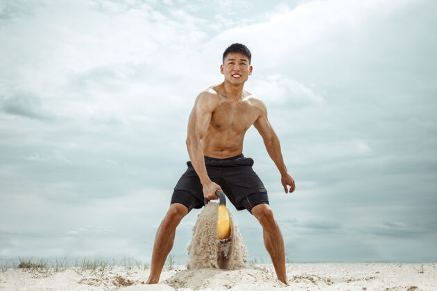 阳刚年轻健康的男子运动员在海滩上做深蹲蹲男性训练