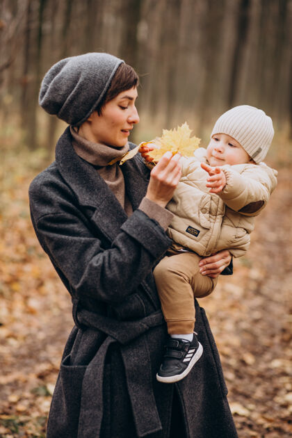 高加索男孩带着小儿子在秋天公园散步的年轻女子父母人年轻