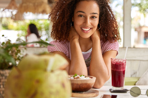 拍摄高兴的黑皮肤女孩的照片正面对着镜头微笑非洲人饮食早餐