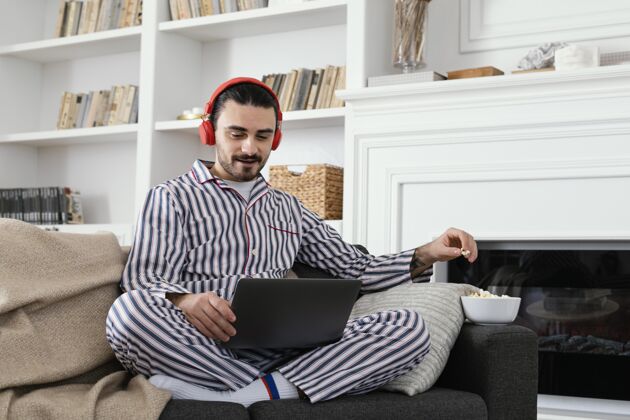 笔记本电脑穿着睡衣的男人在笔记本电脑上玩得很开心耳机室内员工