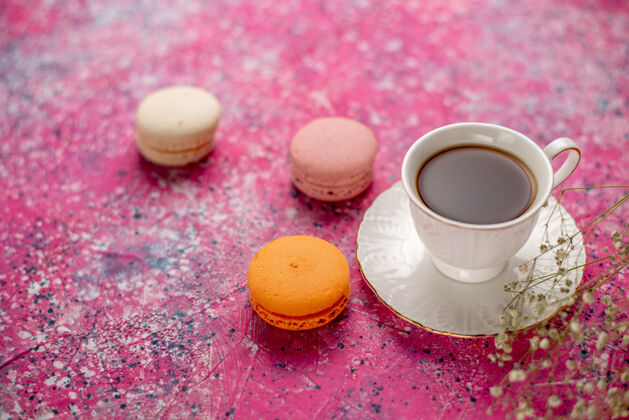 马克杯正面图：茶杯放在盘子里 粉色桌子上放着法国马卡龙饮料咖啡饮料