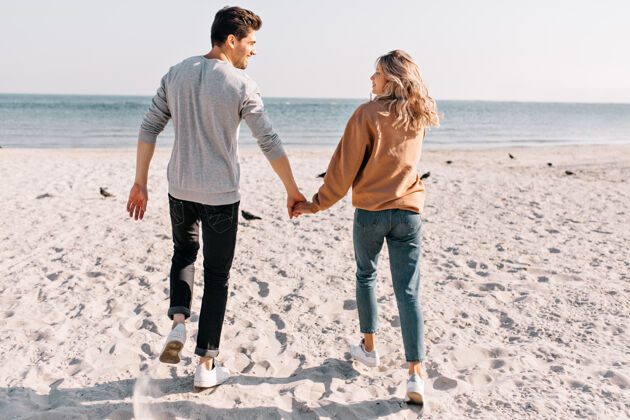 无忧无虑一对积极的情侣微笑着跑向大海美丽女孩在沙滩上休息时与男友牵手的户外写真自由肖像海岸