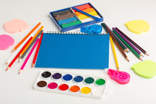 绘图前视图彩色铅笔与油漆和贴纸在浅白色的桌子上书桌油漆蜡笔