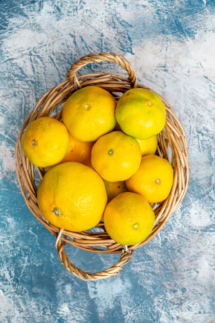 新鲜的普通话俯瞰蓝白色表面柳条篮子上的新鲜柑桔柑橘柠檬柳条