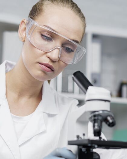 安全眼镜实验室里的女研究员戴着安全眼镜和显微镜女发明家科学家