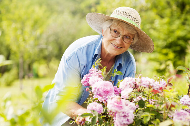 老年成人花园里拿着花的老妇人退休农业眼镜