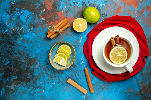 顶部俯瞰一杯茶 用柠檬和肉桂红色披肩在蓝红色的表面复制地方披肩胡椒粉盘子