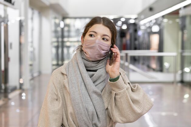 个人戴着医用面罩的女人在打电话新常态人冠状病毒