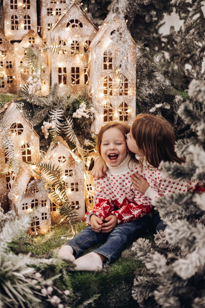 毛衣孩子们站在圣诞装饰的上层美丽圣诞快乐树枝