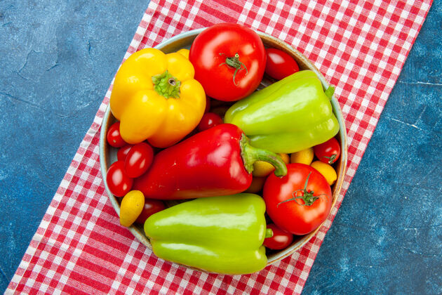 甜椒顶视图新鲜蔬菜樱桃西红柿不同颜色甜椒西红柿cumcuat在碗里红色和白色格子桌布在蓝色的桌子上铃铛景观新鲜蔬菜