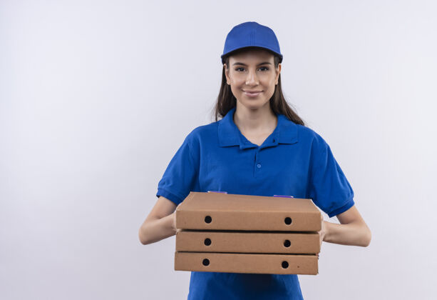 蓝色身穿蓝色制服 戴着帽子的年轻送货员拿着一叠比萨饼盒 面带自信的微笑看着镜头站着自信盒子