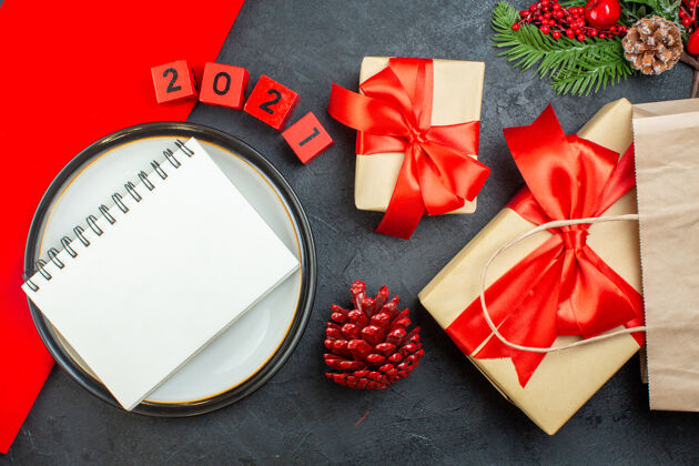 号码上图是漂亮的礼物和笔记本 放在一个圆锥形针叶树的平板上 放在一张深色的冷杉枝数表上冷杉树枝圣诞节