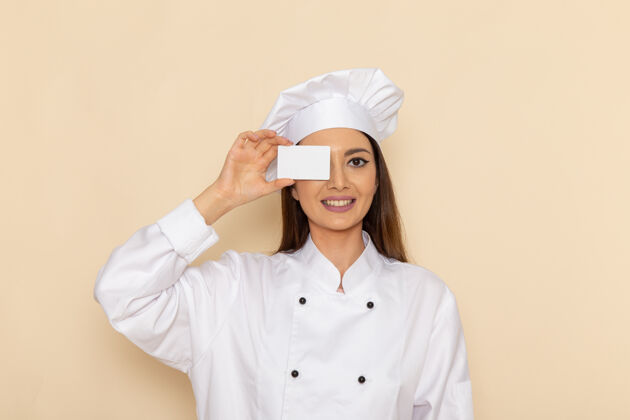 工作身穿白色厨师服的年轻女厨师正对着浅白的墙壁 手里拿着微笑的卡片厨房套装微笑