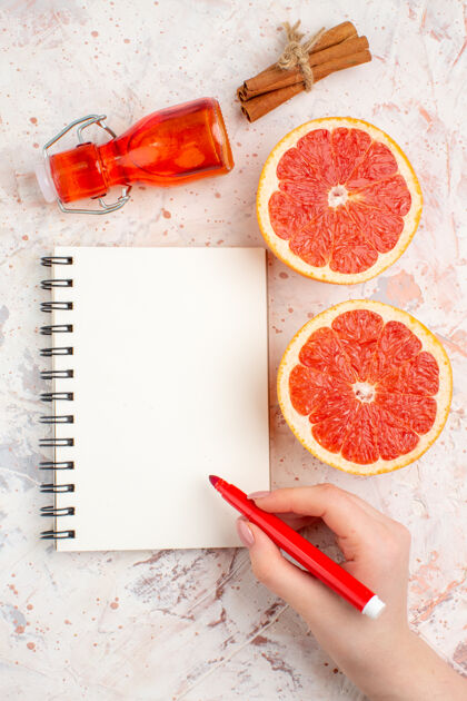 葡萄柚俯视图切割柚子肉桂棒瓶子记事本红色标记在女性手裸体表面肉桂顶部视图