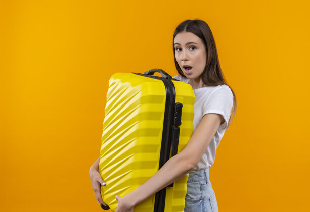 年轻年轻漂亮的旅行女孩拿着手提箱 看上去既惊讶又惊奇惊喜旅行者抱着