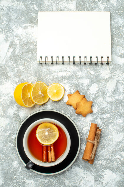 肉桂顶视图一杯茶柠檬片肉桂棒笔记本在灰色的表面磁盘数据笔记本