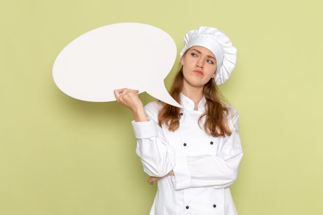 浅绿色身穿白色厨师服的女厨师手持白色标牌 在浅绿色墙上思考女性肖像漂亮