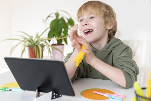 青少年笑笑小男孩在家里用平板电脑设备娱乐男孩