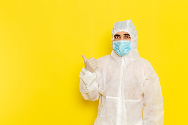 危险身穿白色防护服 带面罩的男性科学工作者的正面图 浅黄色的墙上尺子特殊男性