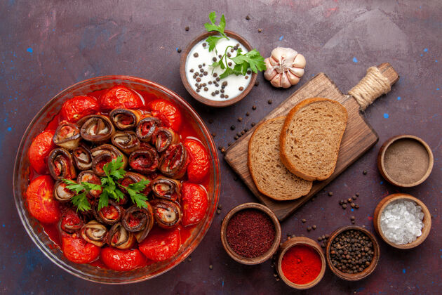 胡椒粉俯瞰煮熟的蔬菜餐美味的西红柿和茄子与面包和调味品在黑暗的表面烹饪盘子膳食