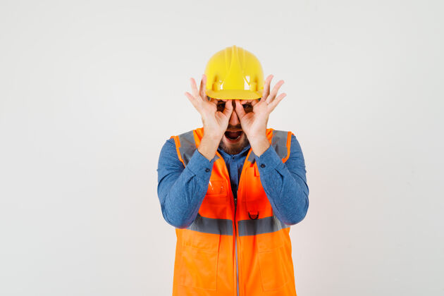 职业年轻的建筑工人在衬衫 背心 头盔显示眼镜的姿态 看起来很有趣 前视图工匠眼镜正面