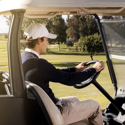 爱好球场上驾驶高尔夫球车的男子侧视图消遣活动玩