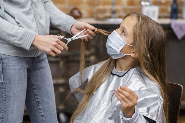孩子戴着医用面具的小女孩在理发发型修身师发型