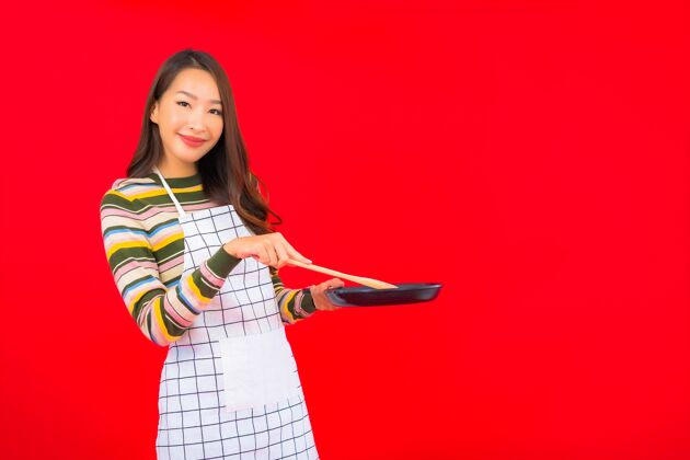 微笑画像美丽的亚洲年轻女子拿着锅准备在红墙上做饭素食者剁碎板