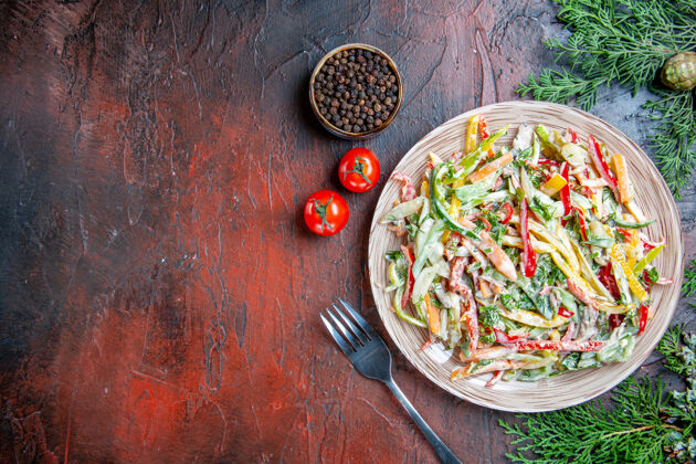 蔬菜沙拉顶视图蔬菜沙拉在盘子叉子上西红柿松枝上暗红色桌子上自由空间松树蔬菜胡椒