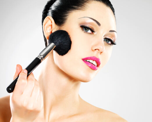 女性用化妆刷在脸上涂腮红的美女肖像套装眼影化妆品