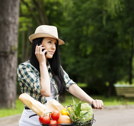 蔬菜打电话的年轻女子享受一个人自行车