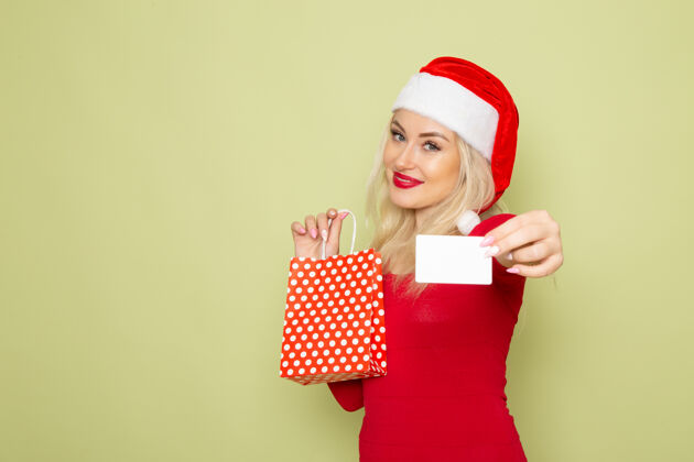 情感正面图漂亮的女人拿着礼物在绿色的墙上小包装情感节日圣诞雪颜色新年雪漂亮的女人漂亮