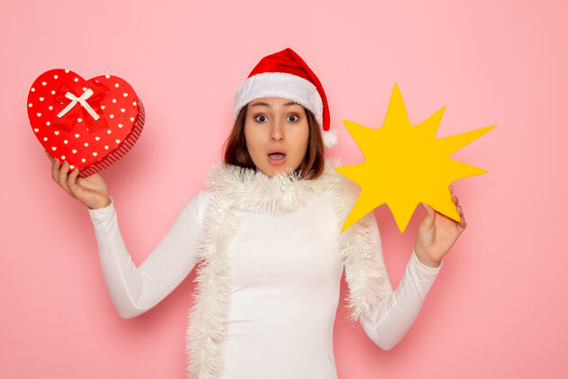 颜色正面图年轻女性手持黄色的身影 呈现在粉色墙壁上雪白的圣诞色新年时尚漂亮肖像圣诞节