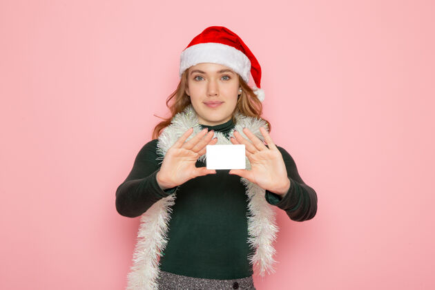 情感正面图年轻女性手持银行卡在粉红色墙上的模型圣诞节s颜色年轻女性孩子