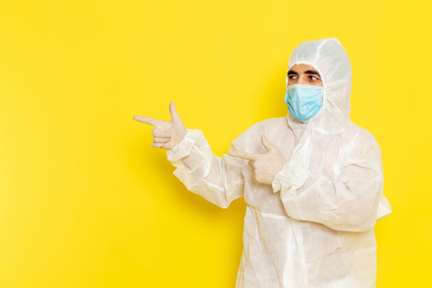 危险身穿白色防护服 带面罩 浅黄色墙壁的男性科学工作者正面图肖像特殊套装