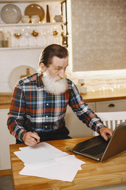 互联网拿着笔记本电脑的老人坐在圣诞装饰品里的爷爷穿手机衫的男人男人眼镜通信