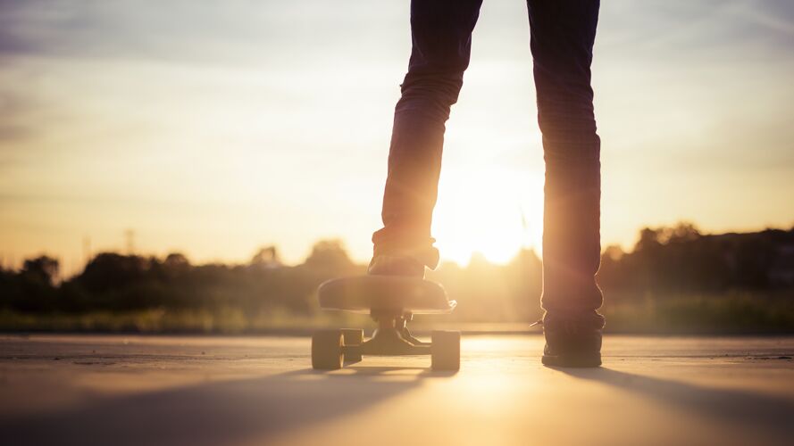 积极特写一个滑板运动员周围的树木在阳光下日落男人溜冰青年