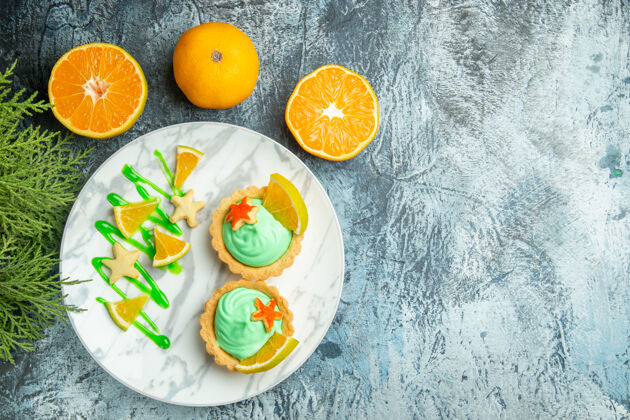 奶油顶视图小馅饼与绿色糕点奶油和柠檬片在盘子上切橘子在黑暗的桌子复制空间小切糕点