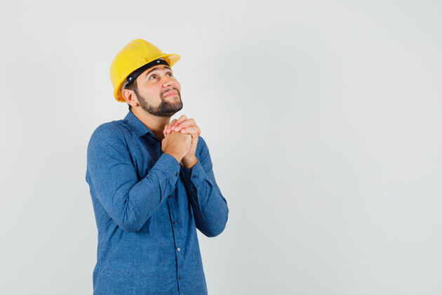 制造身穿衬衫 头戴钢盔的年轻工人双手合十祈祷 看上去充满希望工作合作分析