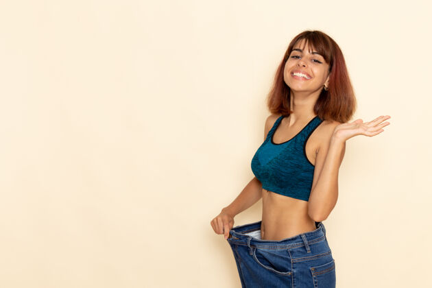 衬衫年轻女性穿着蓝色衬衫 身体健康 正对着浅白的墙壁检查体重锻炼身体运动员