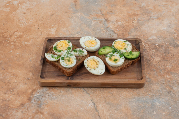 板两杯烤黄瓜和煮鸡蛋在大理石表面吐司木头煮的