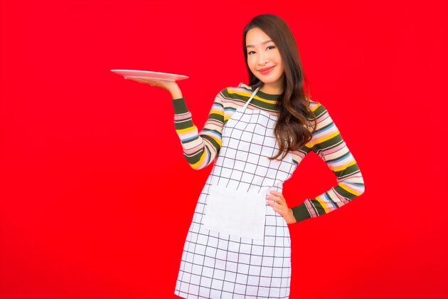 健康画像美丽的亚洲年轻女子在红墙上展示空盘子准备房子亚洲