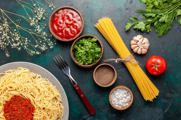 餐俯瞰煮熟的意大利面食 蓝色表面有肉和不同的调味品调味品顶部生的