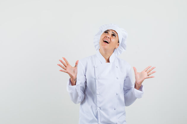 柜台女厨师举手 身穿白色制服抬头 神情激动厨房制服专业