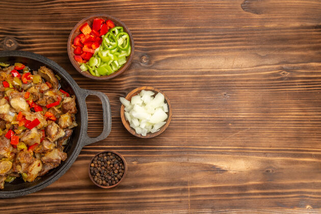 沙拉俯瞰木制棕色桌子上的熟肉蔬菜餐和新鲜的甜椒片桌子胡椒烹饪